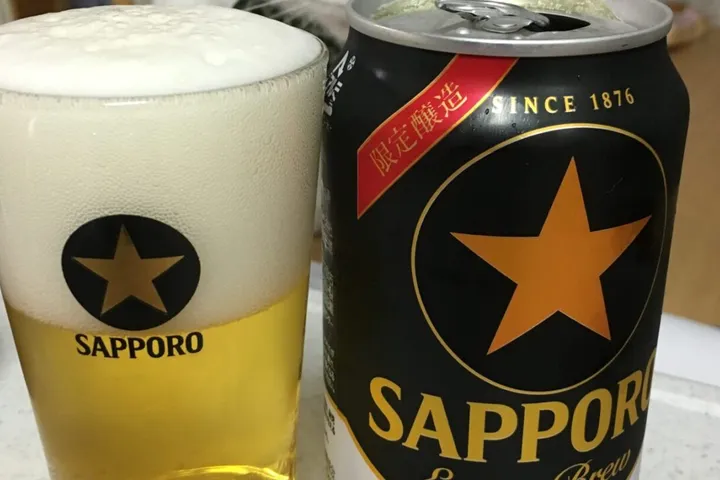 グラスに注いだビールと黒ラベルの缶