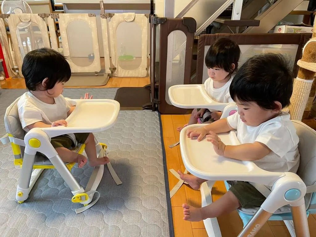 3脚の椅子に座り、互いの方向を向く三つ子