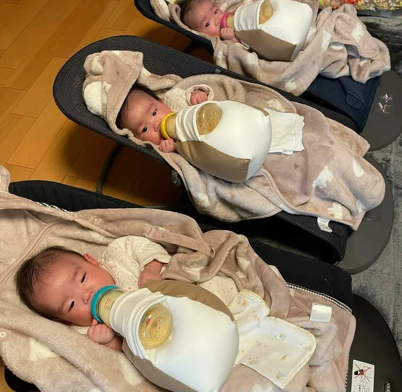 並んで寝ながら同時にミルクを飲む三つ子