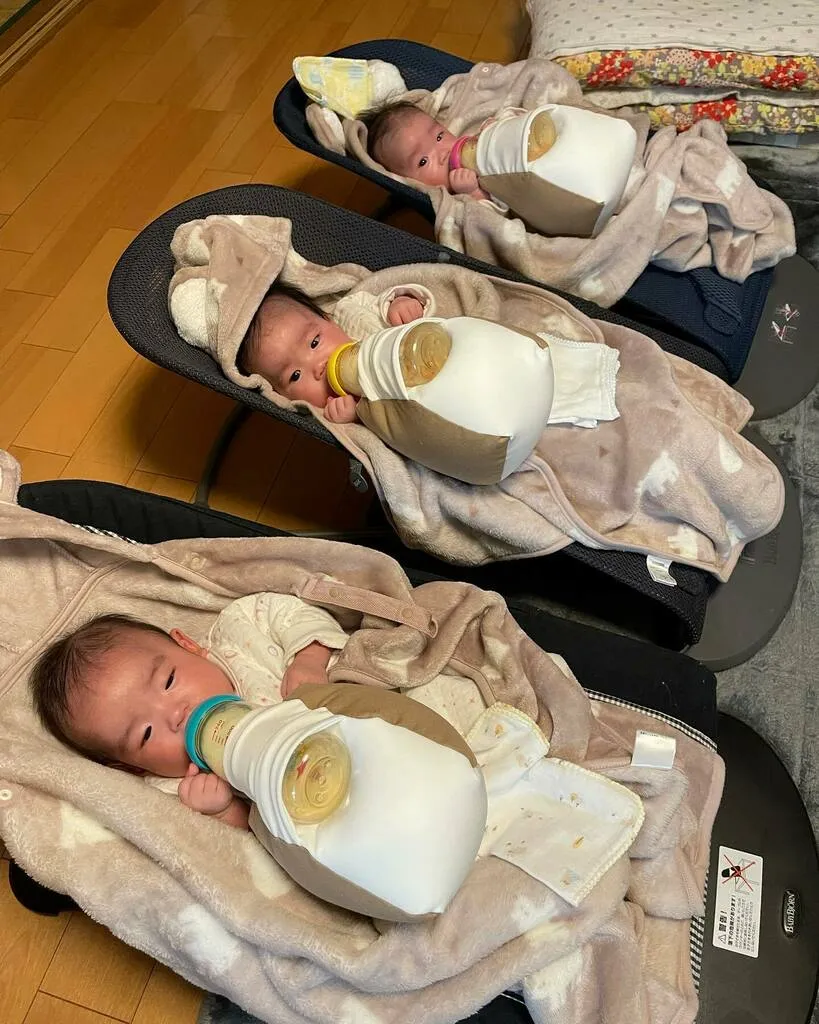 3台のバウンサーに並び、授乳補助具でミルクを飲む三つ子
