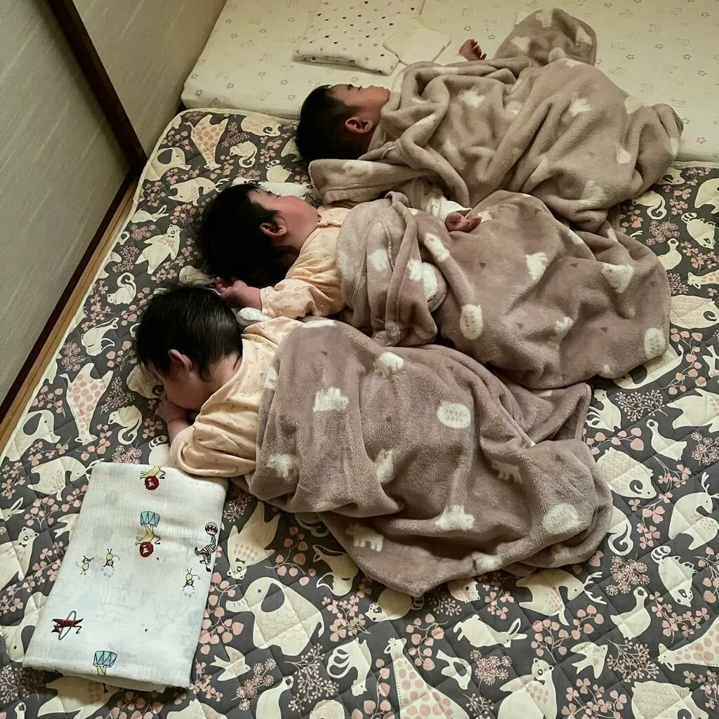 同じ布団の上で毛布を掛けて眠る三つ子