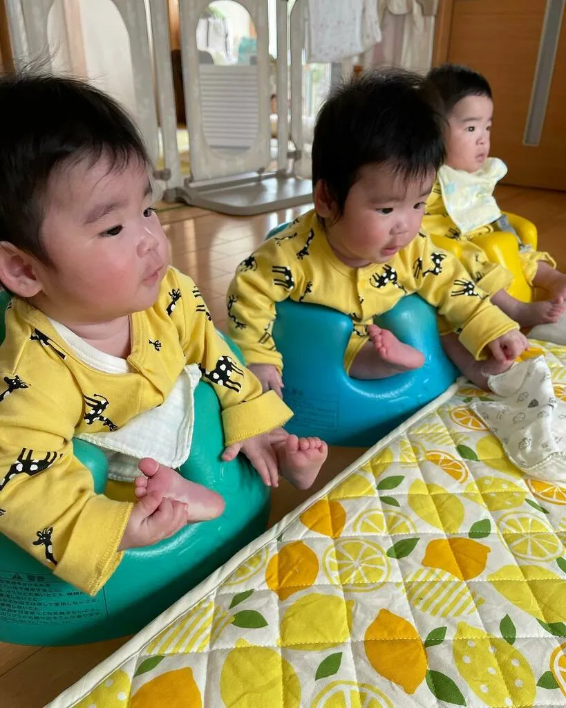 同じ服とスタイで並び、離乳食を待つ三つ子