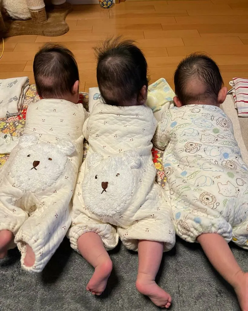 後ろ姿で3人並び、うつ伏せの練習をする三つ子