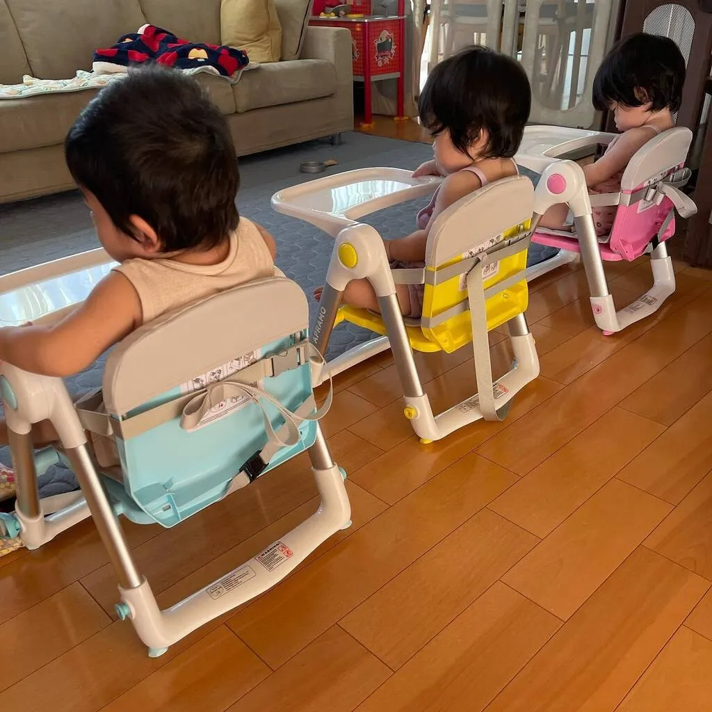3脚の椅子に並んで座り、離乳食を待つ三つ子